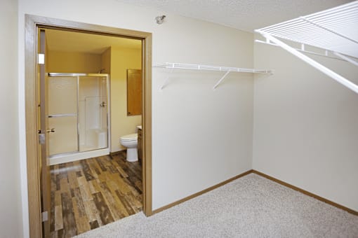 A white closet with a white shelf and a white toilet in the bathroom.