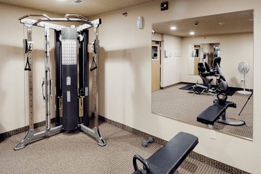 A gym with a mirror, weights, and a leg press machine.
