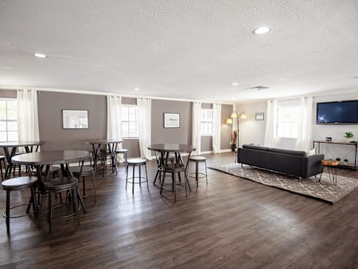 A living room with a grey couch, a round table, and chairs.