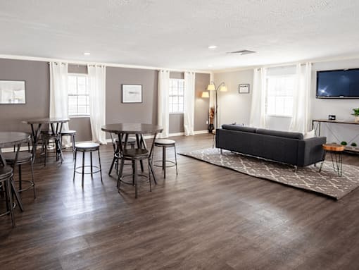 A living room with a grey couch, a television, and a dining table with chairs.