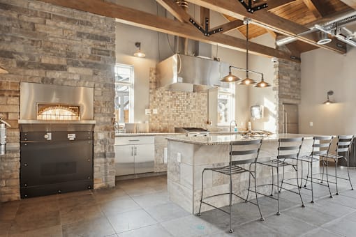 A modern kitchen with a stone fireplace and bar stools.