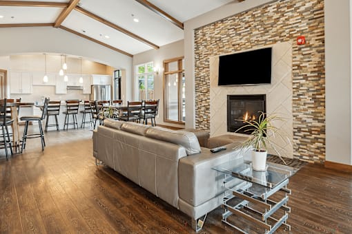 A modern living room with a stone fireplace and a glass coffee table.