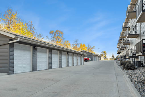 A row of garage doors in front of a building with a red car parked in the middle.