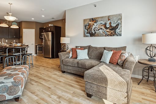 A living room with a grey couch and a wood-look floor.