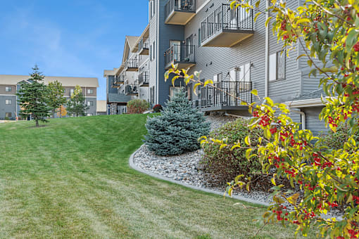 A grey apartment building with a green lawn in front.