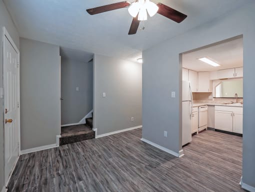 an empty living room and kitchen with a ceiling fan