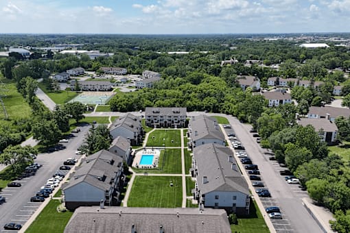 A bird's eye view of a residential area with houses, a swimming pool, and a parking lot.