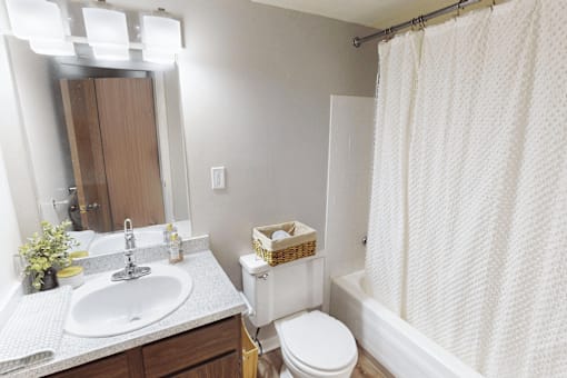 A white bathroom with a sink, toilet, and shower.