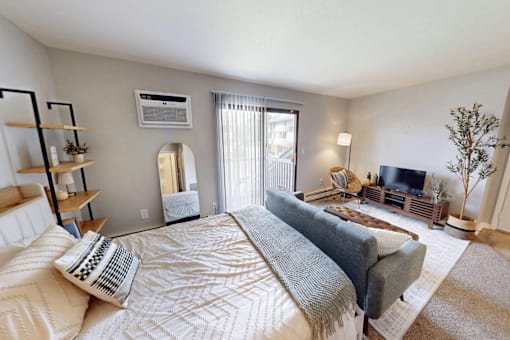 A well-lit bedroom with a large bed and a television.