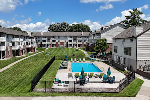 A swimming pool surrounded by a black fence and chairs.