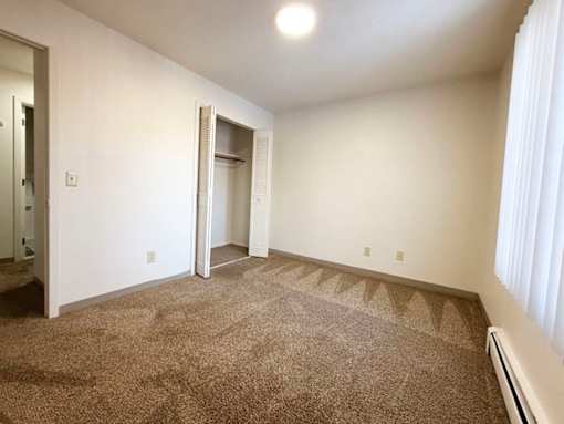 A room with a carpeted floor and a doorway leading to another room.