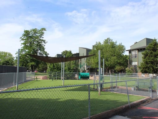 a tennis court in a park with buildings in the background
