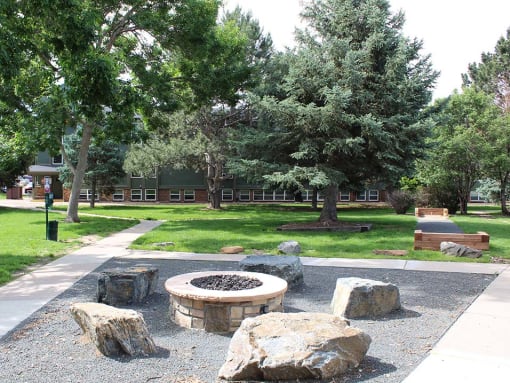 a firepit and rocks in a park with a building in the background