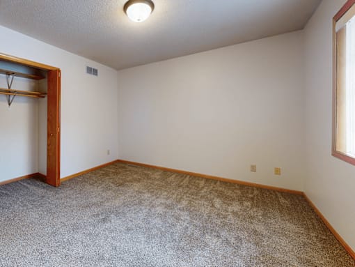 A room with a carpeted floor and a door on the left.