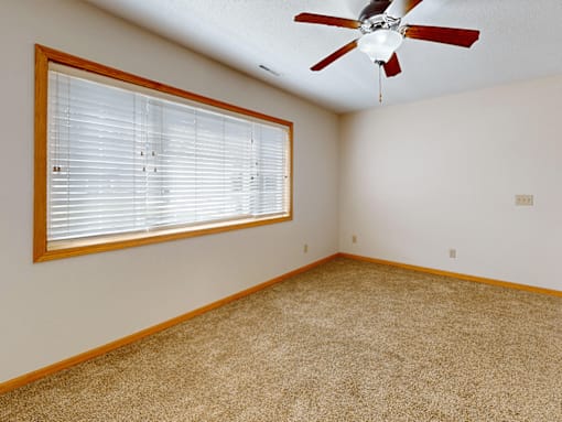 A room with a ceiling fan and a window with blinds.