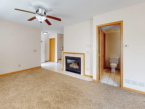 A living room with a fireplace and a ceiling fan.