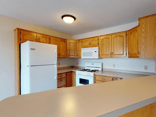A kitchen with white appliances and wooden cabinets.