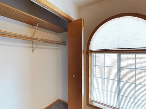 A white wall with a wooden door and a window with blinds.