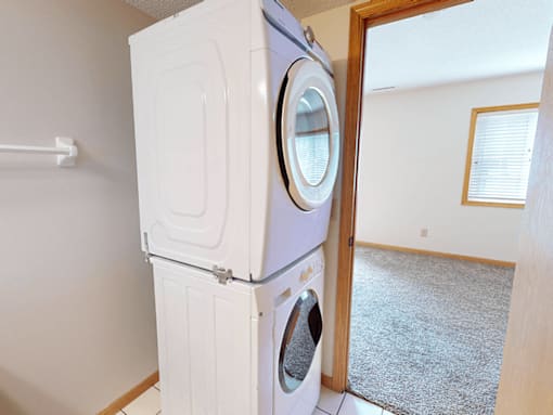 A white washing machine and dryer stacked on top of each other in a laundry room.