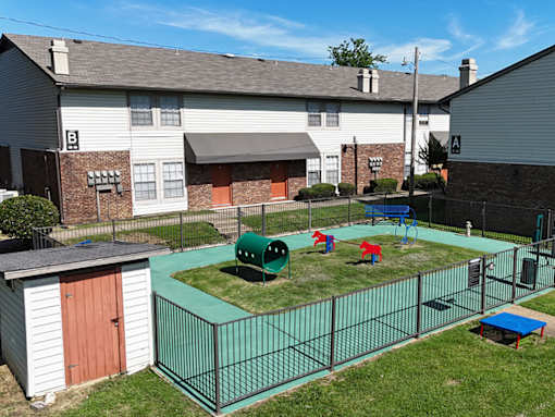 A playground area with a green fence and a red and blue slide.
