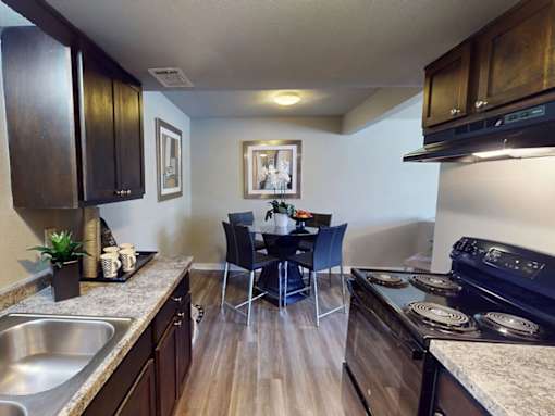 A kitchen with dark wood cabinets and a black stove top oven.