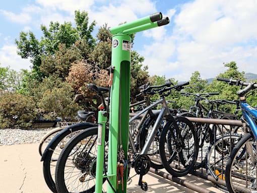 A green bike rack with bikes parked on it.