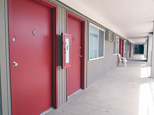 A long hallway with red doors and white walls.