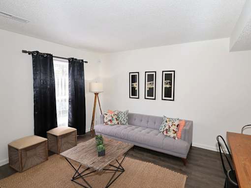 A living room with a grey couch, a wooden coffee table, and a black chair.