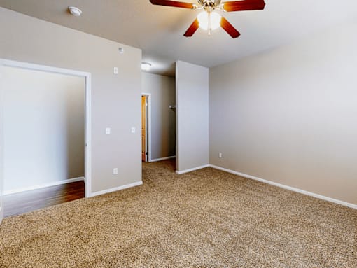 A room with a ceiling fan and carpeted floor.