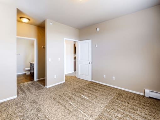 A room with a carpeted floor and a door on the right side.