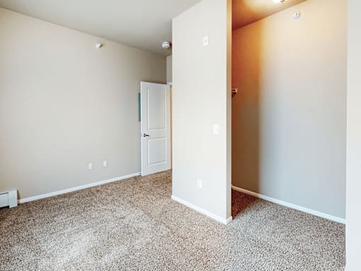 A room with a carpeted floor and a white door.