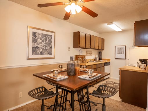 a dining area with a table and chairs and a kitchen in the background