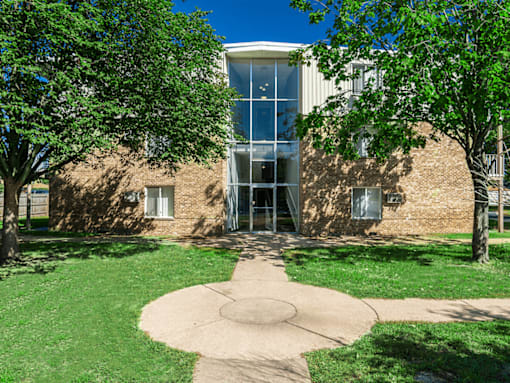 A building with a glass entrance is surrounded by trees.