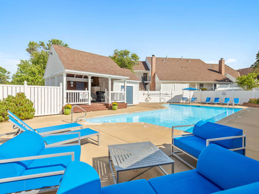 a swimming pool with blue chairs in front of a house