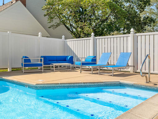 a swimming pool with blue lounge chairs next to it