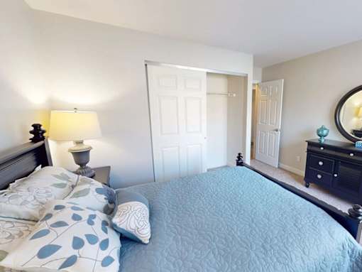 A bedroom with a bed, dresser, and mirror.