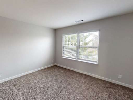 A room with a window covered by white blinds.