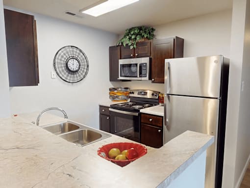 A kitchen with a stainless steel refrigerator, microwave, and oven.