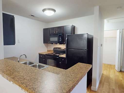 A kitchen with black appliances and a granite countertop.