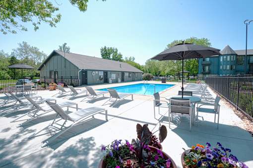 A pool area with sun loungers and a black umbrella.
