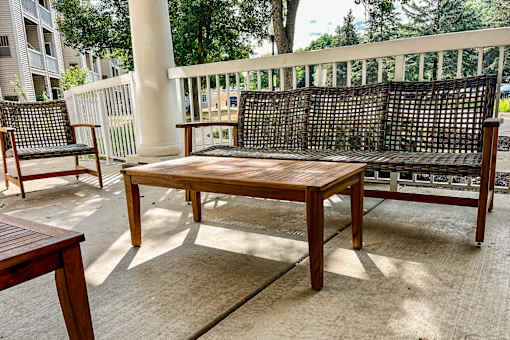 A wooden bench with a backrest is situated on a patio.
