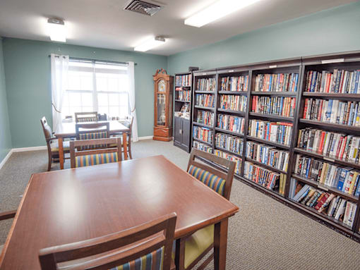 A room with a long table and chairs and a bookshelf filled with books.