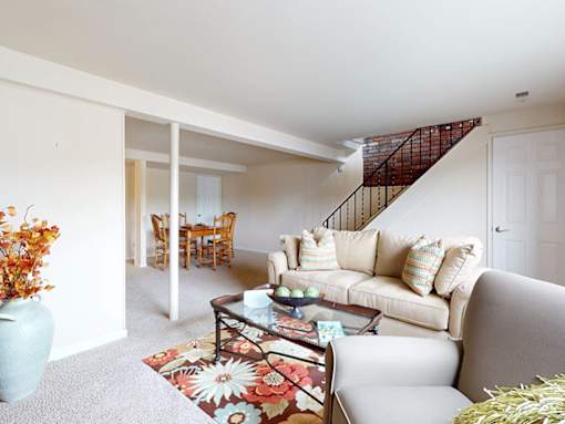 A living room with a couch, coffee table, and a staircase.