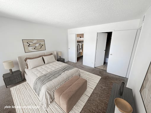 A bedroom with a large bed and a wardrobe in the background.