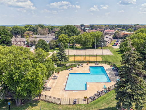 an aerial view of a swimming pool in a park with trees