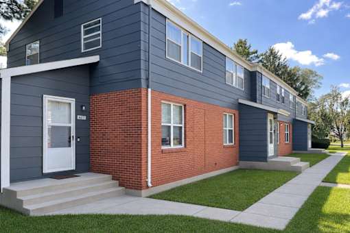 A modern two-story house with a blue exterior and a red brick section.