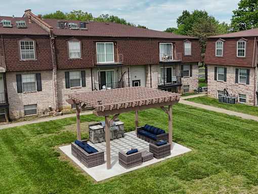 A patio with a pergola and couches is in front of a building.