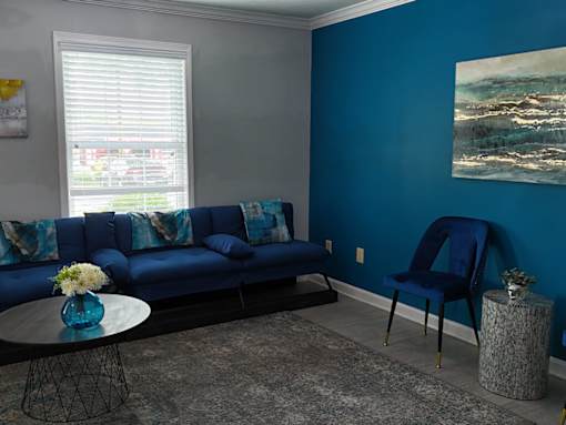 A blue sofa with a matching chair and a painting on the wall.