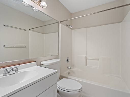 A white bathroom with a toilet, sink, and bathtub.