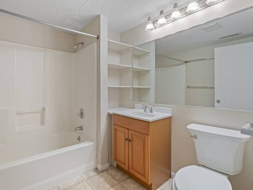 A white bathroom with a wooden cabinet and a white toilet.
